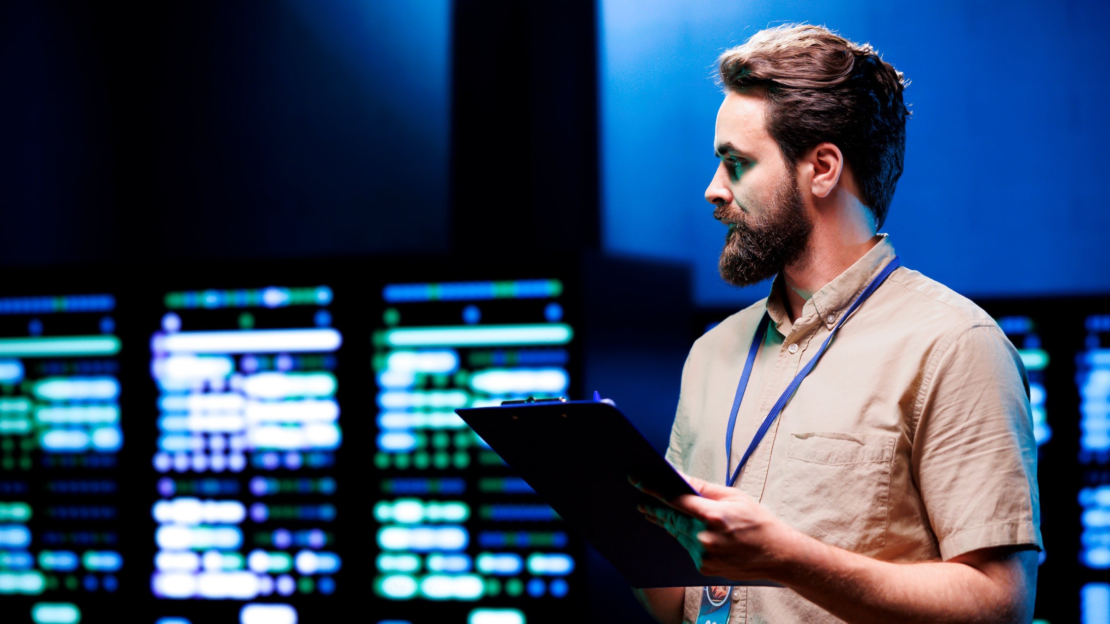 A man standing in a server room with a clipboard.