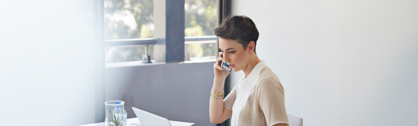 A woman with short hair talks on the phone while speaking on her phone