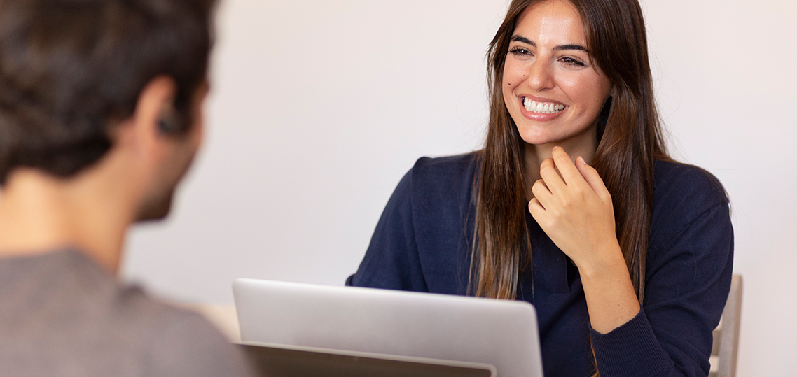 A woman smiles as she looks at the man in front of her.