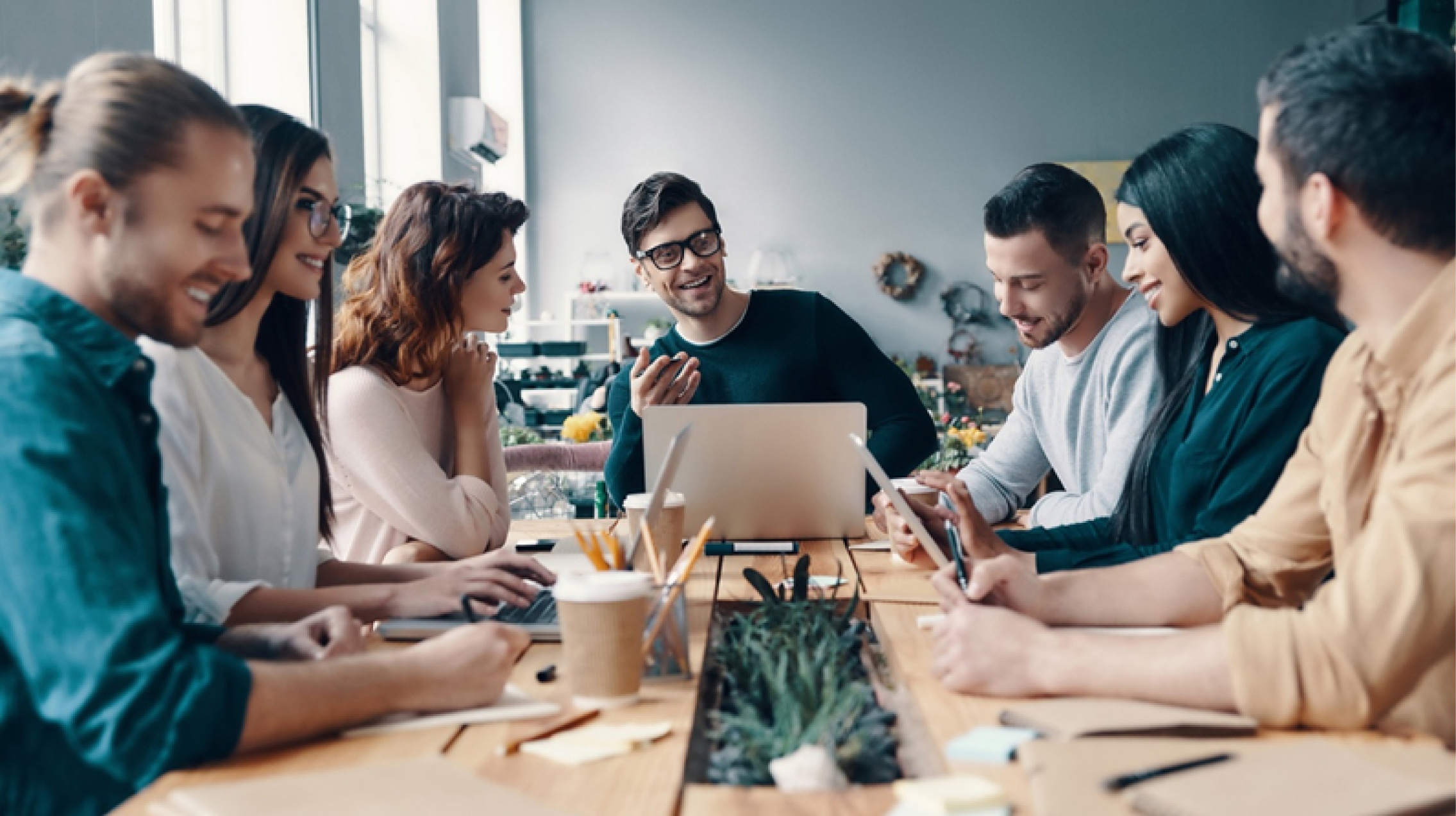 Colleagues sitting around a table and smiling and talking